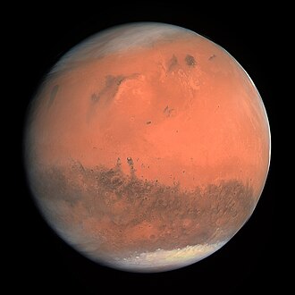 Mars appears as a red-orange globe with darker blotches and white icecaps visible on both of its poles.